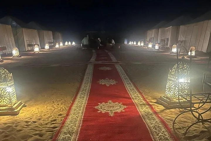 Red carpet leading to desert tents illuminated by lanterns at night