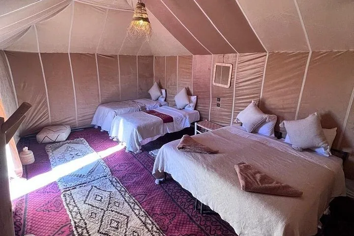 Interior of a desert tent with three single beds and traditional rugs